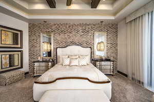 Carpeted bedroom featuring brick wall and beam ceiling