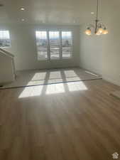 Empty room with light hardwood / wood-style flooring, a chandelier, and a textured ceiling