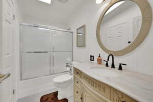 Full bathroom with tile patterned flooring, toilet, vanity, and shower / bath combination with glass door