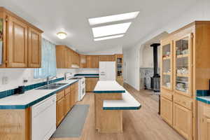 Kitchen featuring white appliances, lofted ceiling, sink, light wood-type flooring, and a kitchen island