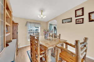 Dining space with light hardwood / wood-style floors and an inviting chandelier