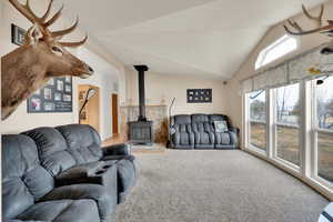 Carpeted living room with a wood stove and lofted ceiling