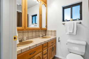 Bathroom with vanity, toilet, and backsplash