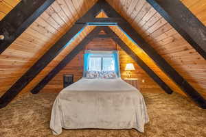 Unfurnished bedroom featuring vaulted ceiling with beams, wooden walls, and carpet floors