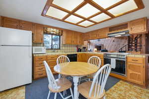 Kitchen with sink, white appliances, kitchen peninsula, and tile countertops