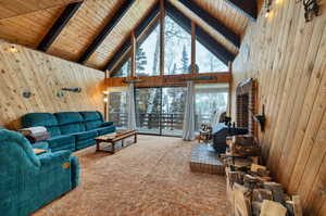 Living room with carpet flooring, wooden walls, high vaulted ceiling, wood ceiling, and beamed ceiling