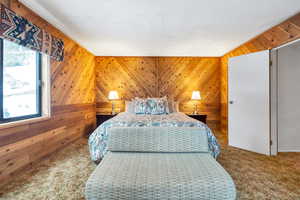 Bedroom with wooden walls and carpet flooring