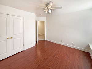 Unfurnished bedroom featuring ceiling fan, a closet, and dark wood-type flooring