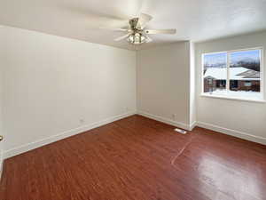 Empty room featuring hardwood / wood-style flooring, ceiling fan, and a textured ceiling