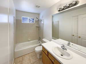 Full bathroom with vanity, tile patterned flooring, tiled shower / bath, and toilet