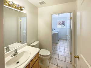 Bathroom with washing machine and dryer, tile patterned flooring, vanity, and toilet