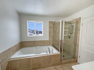 Bathroom featuring shower with separate bathtub and a textured ceiling