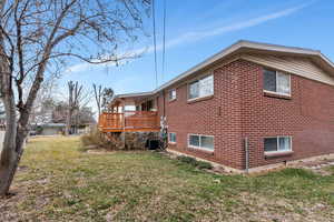 View of property exterior featuring a lawn, a wooden deck, and central AC unit