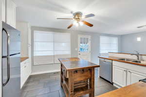 Kitchen featuring white cabinetry, sink, stainless steel appliances, and decorative light fixtures