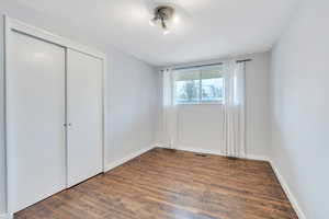 Unfurnished bedroom featuring a closet and dark hardwood / wood-style floors