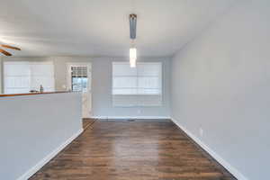 Unfurnished dining area with ceiling fan and dark wood-type flooring