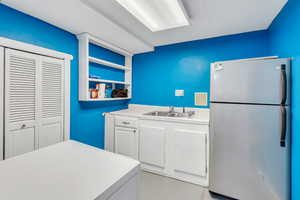 Kitchen with sink, stainless steel refrigerator, and white cabinets