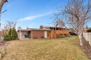 Rear view of house with a lawn and a wooden deck