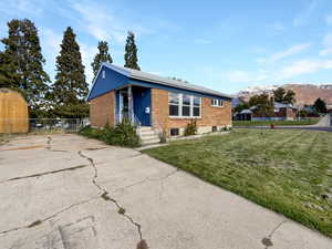 View of front of home with a mountain view and a front lawn