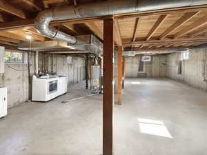 Basement featuring water heater and washing machine and clothes dryer