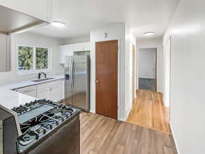 Kitchen featuring white cabinetry, dishwasher, stainless steel fridge with ice dispenser, and gas range oven