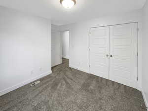 Unfurnished bedroom featuring a closet and dark colored carpet