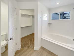 Bathroom featuring toilet, hardwood / wood-style flooring, and a bath