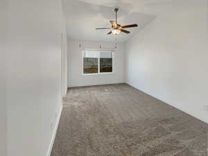 Spare room with vaulted ceiling, carpet flooring, and ceiling fan