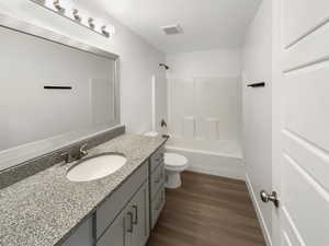 Full bathroom with hardwood / wood-style floors, shower / bath combination, vanity, and toilet