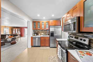 Kitchen with appliances with stainless steel finishes, decorative backsplash, sink, and light carpet