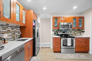 Kitchen with appliances with stainless steel finishes, light tile patterned flooring, sink, and tasteful backsplash