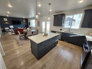 Kitchen featuring range with gas stovetop, dishwasher, decorative light fixtures, a center island, and sink