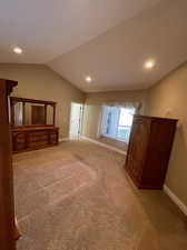 Unfurnished living room featuring light carpet and lofted ceiling