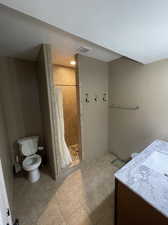 Bathroom featuring a shower with curtain, vanity, a textured ceiling, toilet, and tile patterned floors