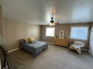 Bedroom with ceiling fan, carpet flooring, and a textured ceiling