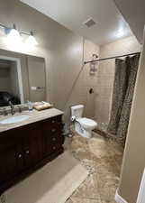 Bathroom featuring a shower with shower curtain, vanity, and toilet