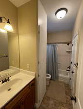 Full bathroom with toilet, vanity, a textured ceiling, and shower / bath combo with shower curtain