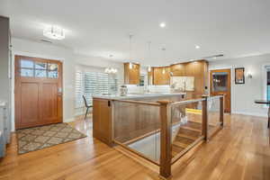 Kitchen with light wood-type flooring, kitchen peninsula, tasteful backsplash, and hanging light fixtures