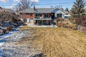 Back of property featuring a patio, a balcony, and a lawn