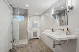 Bathroom with tasteful backsplash, tile walls, and a shower with euro door