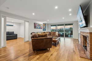 Living room with a brick fireplace and light hardwood / wood-style floors