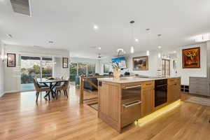 Kitchen with a kitchen island, decorative light fixtures, light hardwood / wood-style floors, ceiling fan, and black appliances