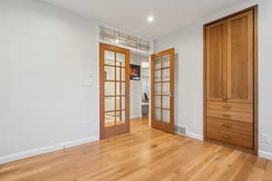 Spare room with french doors and light hardwood / wood-style floors