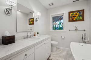 Bathroom with a tub to relax in, toilet, and vanity