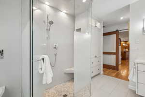 Bathroom featuring tile walls, vanity, a tile shower, and tile patterned floors