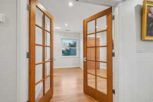 Hallway with light wood-type flooring and french doors