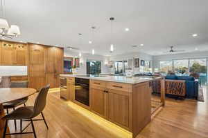 Kitchen with light hardwood / wood-style flooring, black appliances, a kitchen island, and decorative light fixtures