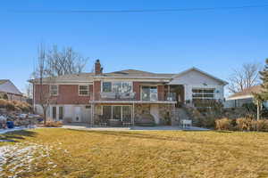 Back of property featuring a patio, a balcony, and a yard