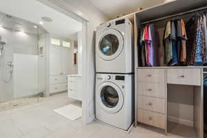 Laundry area featuring light tile patterned floors and stacked washer / drying machine