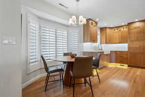 Dining area featuring sink, a notable chandelier, and light hardwood / wood-style floors